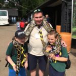 Paul Goffin accompanied by two Cubs with a long snake around their necks.